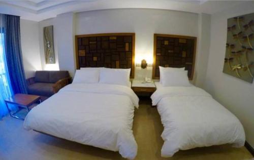 two beds in a room with a room with a couch at MO2 Lagoon Coron in Coron