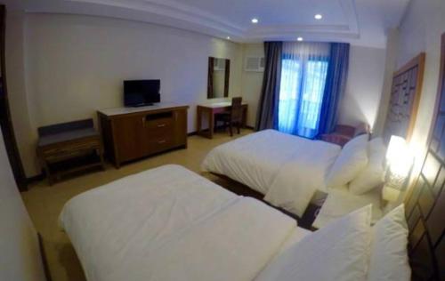 a hotel room with two beds and a television at MO2 Lagoon Coron in Coron
