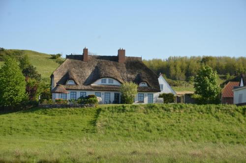 an old house with a thatched roof on a hill at Reethaus Zickersche Berge - Apt. 01 in Gager