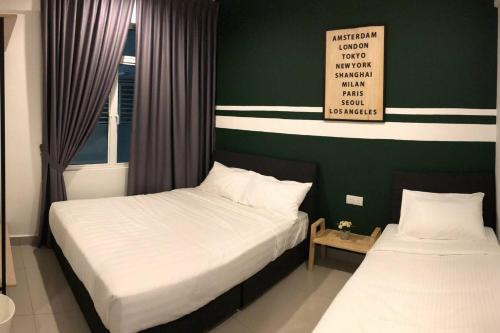 two beds in a bedroom with a green wall at Dream of the summer Ipoh in Ipoh