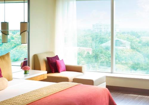 a bedroom with a bed and a large window at Vivanta Coimbatore in Coimbatore