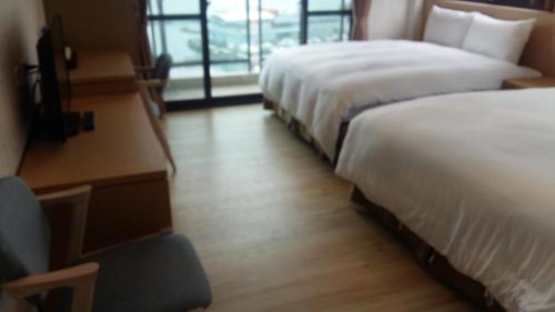 a hotel room with two beds and a chair at Yi Da Lakeside Hotel in Yuchi