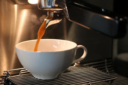 a coffee being brewed into a white cup on a rack at Hotel Rossi in Berlin