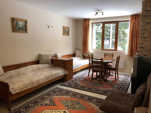 een woonkamer met een bed, een tafel en stoelen bij Manastira 2 apt Emo Pamporovo in Pamporovo