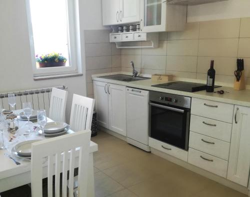 a kitchen with white cabinets and a table and a sink at Apartment Luce in Pićan