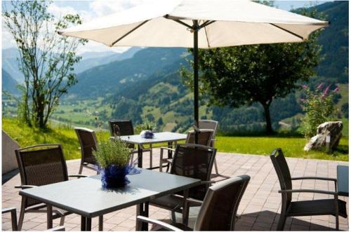 a patio with tables and chairs with an umbrella at Appartements Hartlbauer in Dorfgastein