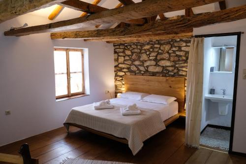 a bedroom with a bed and a stone wall at Linos Traditional Cottage in Theológos