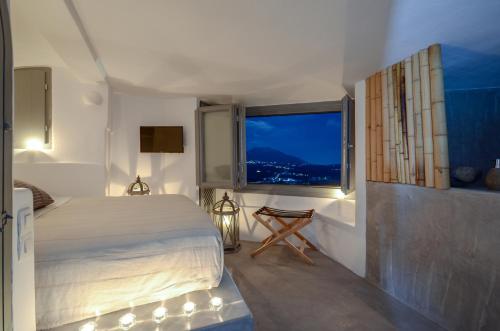 a bedroom with a bed and a large window at Nissos House Santorini in Akrotiri