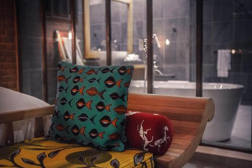 a bench with a cushion and a pillow with fish patterns at Le Patio in Lomé