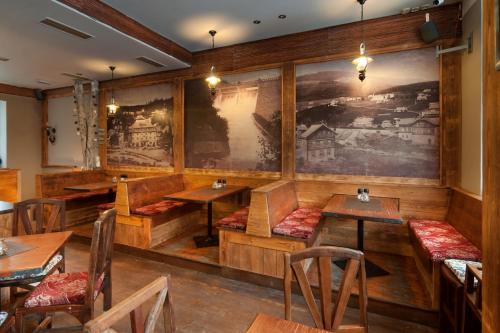 a restaurant with wooden tables and chairs and a painting on the wall at Wellness Hotel Grand in Špindlerův Mlýn
