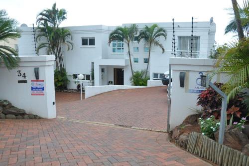 un grand bâtiment blanc avec des palmiers et une allée. dans l'établissement 34 on Milkwood, à Durban