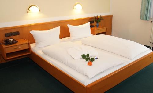 a bed in a hotel room with a flower on it at Hotel Lengenfelder Hof in Lengenfeld