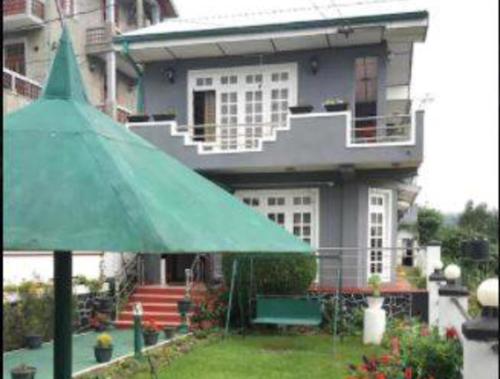a green umbrella in front of a house at New Royal Mount Hotel in Nuwara Eliya