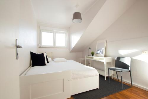 ein weißes Schlafzimmer mit einem weißen Bett und einem Stuhl in der Unterkunft Capital Flat 70m2 in Luxemburg (Stadt)