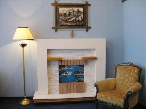 a living room with a fireplace with a chair and a lamp at Hotel European in Dnipro