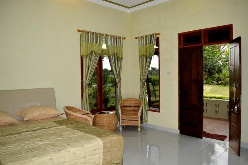 1 dormitorio con 1 cama y algunas sillas y ventanas en LANDBOW GREEN VILLAGE Homestay Trekking & Village Tour, en Bukit Lawang