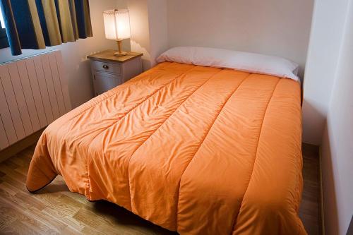 an orange bed in a room with a lamp at Apartamentos Laurel in Logroño