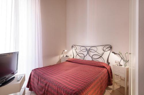 a bedroom with a bed with a red blanket and a tv at Residence San Lorenzo in Verona