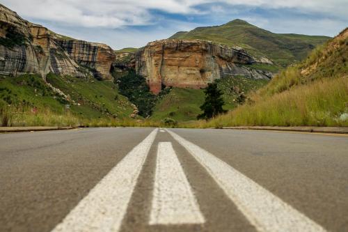 an empty road with mountains in the background at Three Tree Hill Lodge in Bergville