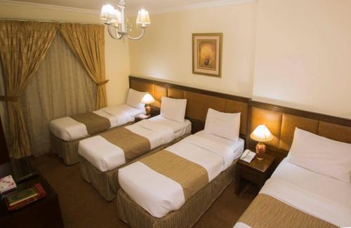 a hotel room with three beds and a chandelier at Anwar Al Zahraa Hotel in Al Madinah
