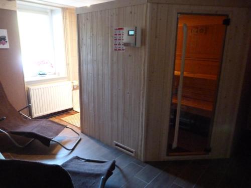 a room with a wooden wall with a glass door at Domaine Des Hauts Viaux in La Bresse