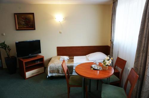 um quarto de hotel com uma mesa e uma cama e uma televisão em Pod Szczęśliwą Gwiazdą em Cekanowo