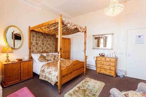 a bedroom with a canopy bed with a dresser and a mirror at Belmont Hotel in Blackpool