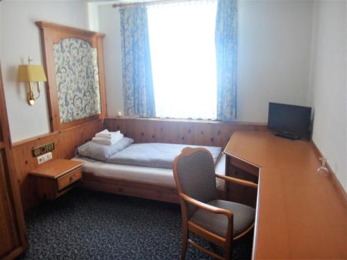a small room with a bed and a desk and a window at Bodenseehotel Lindau in Lindau