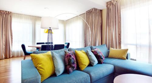 a blue couch with colorful pillows in a living room at Home Hotel Bryggeparken in Skien