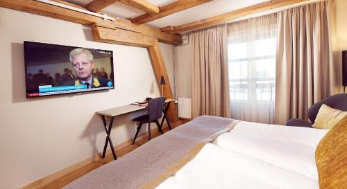 a hotel room with a bed and a tv on the wall at Home Hotel Bryggeparken in Skien