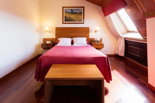 a bedroom with a large bed with a red blanket at Hotel Valencia in Ferrol