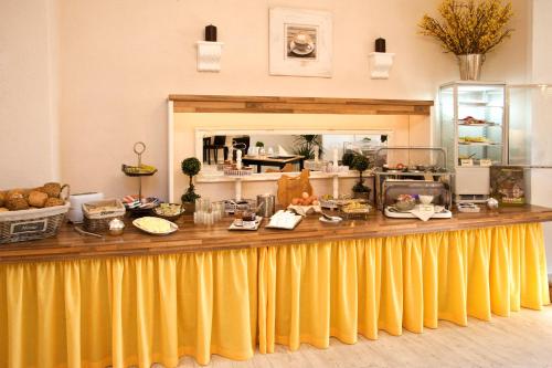Hotel Garni Zum Grünen Baum في هوفيلهوفير: بوفيه ذو ستائر صفراء وطعام موضوع على منضدة