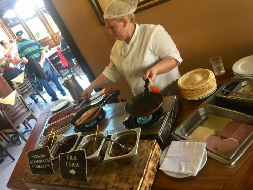 a woman cooking food in a pot on a stove at Flat Wish Serrano Hotel in Gramado