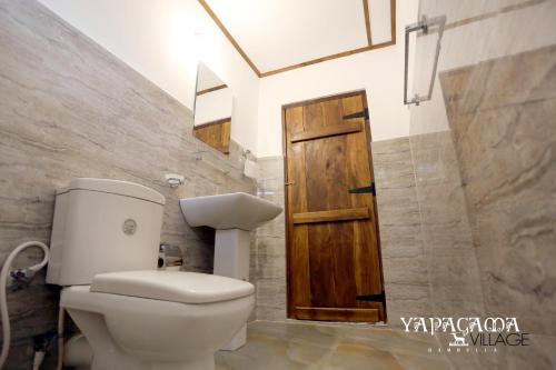 ダンブッラにあるYapagama Villageのバスルーム(トイレ付)、木製のドアが備わります。