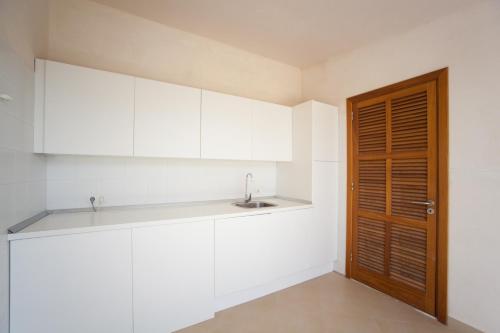 een keuken met witte kasten, een wastafel en een deur bij Ca Na Molinera in Sant Joan
