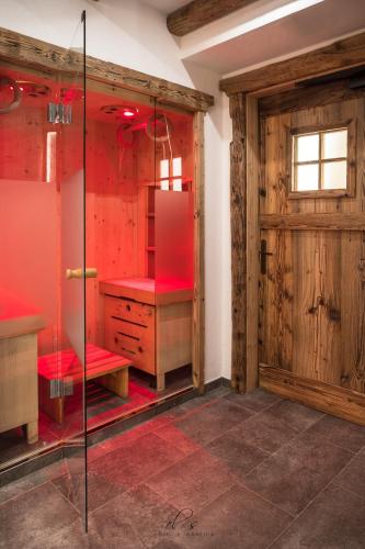 a bathroom with red walls and a wooden door at Residence Lastè in Moena