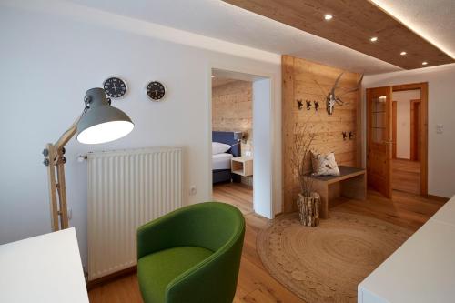 a living room with a green chair and a bedroom at Alpenchalet Vils Tirol in Vils