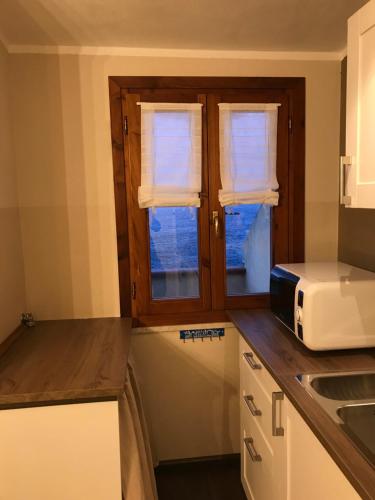 a kitchen with a counter top with a microwave and windows at Il doppio nodo in Castelsardo