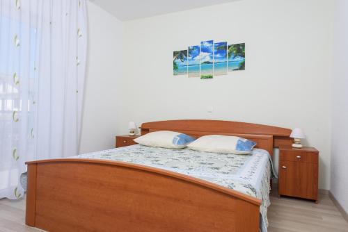 a bedroom with a wooden bed with two pillows at Apartments & Rooms Seaside in Kaštela