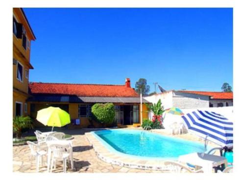 a pool with chairs and umbrellas next to a house at Hotel Sao Gabriel in São Gabriel