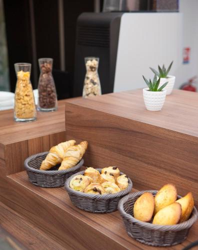 three baskets of bread and pastries on a shelf at Hôtel Métropole centre ville in Boulogne-sur-Mer