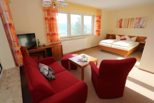 a living room with red chairs and a red couch at Hotel Waldblick in Treffurt