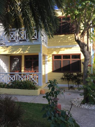 a yellow house with a palm tree in front of it at Buccaneer Beach Club in Dickenson Bay