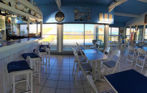 a restaurant with tables and chairs and a clock on the wall at Hotel Bord A Bord in Noirmoutier-en-l'lle