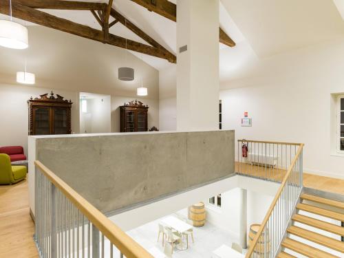 una escalera en un loft con paredes blancas y techos de madera en Hôtel Le Domaine Du Moulin de Monjous, en Gradignan