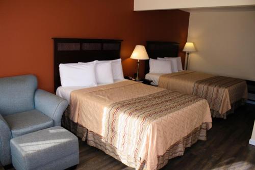 una habitación de hotel con 2 camas y una silla en Valley Oaks Inn Woodland, en Woodland
