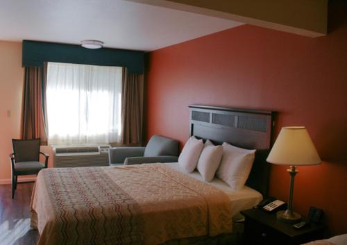 ein Hotelzimmer mit einem Bett und einem Wohnzimmer in der Unterkunft Valley Oaks Inn Woodland in Woodland