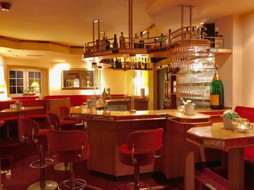 a bar in a restaurant with red chairs at Ringhotel Roggenland in Waldeck