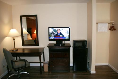Camera con TV, scrivania e specchio. di Valley Oaks Inn Woodland a Woodland