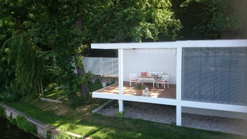a backyard with a table and a white pergola at Marina Hausboote und Seelodge in Berlin